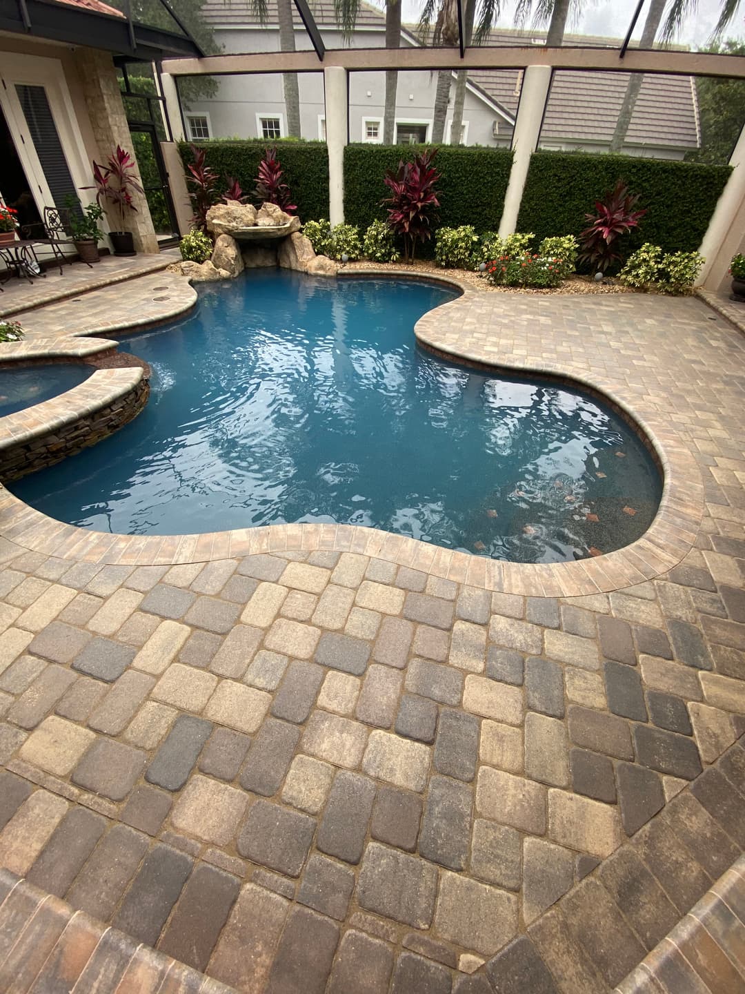 Luxury backyard with a curvy pool, stone patio, and tropical landscaping.