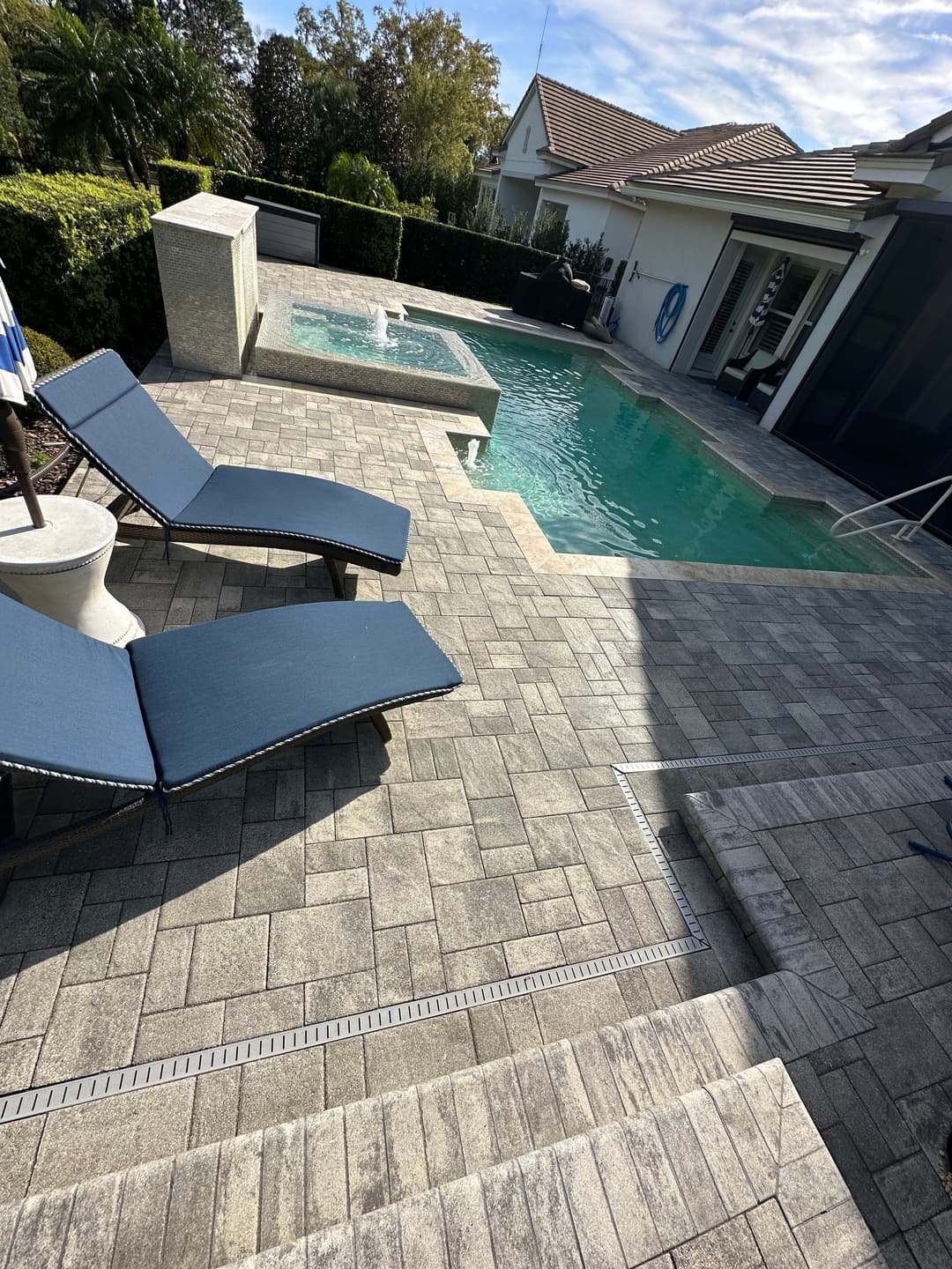 Luxurious backyard with a pool, spa, and lounge chairs in a sunlit setting.