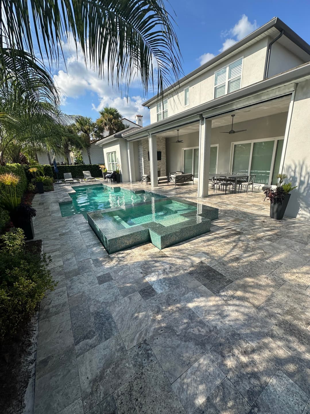 Luxury backyard with pool, spa, and patio surrounded by tropical landscaping.