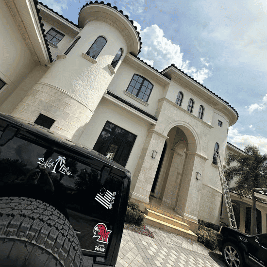 Luxury modern mansion with elegant architecture and a man on a ladder for maintenance.