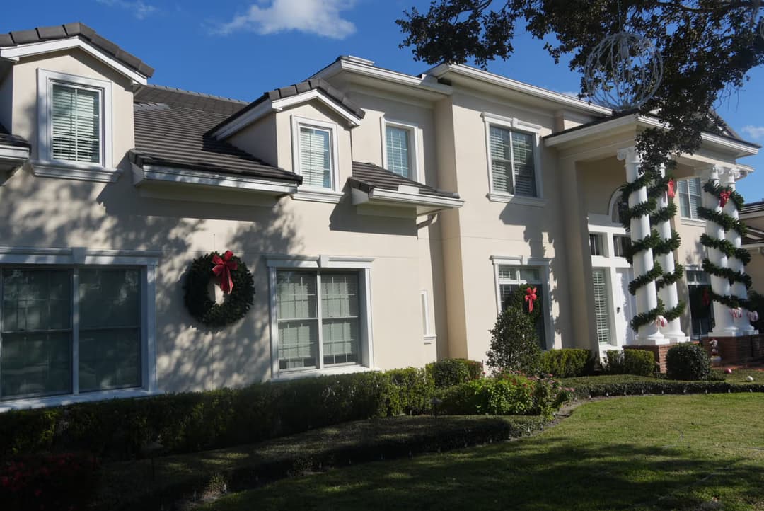 Modern home decorated for Christmas with wreaths and greenery on windows.