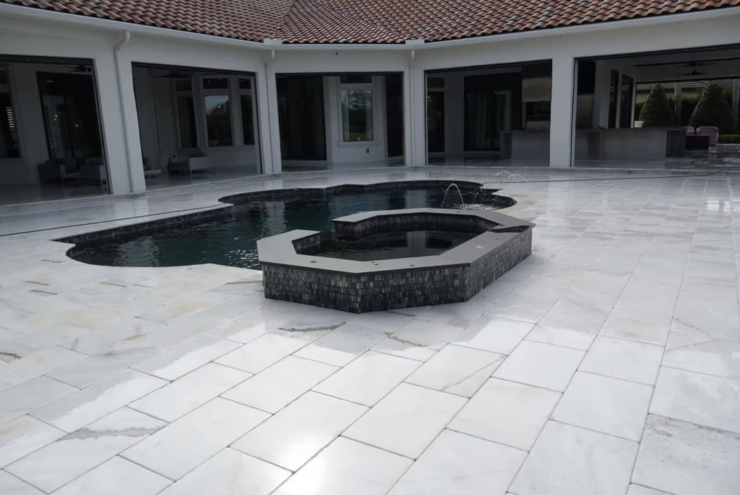 Luxury outdoor pool area with modern tile, sleek design, and elegant water features.